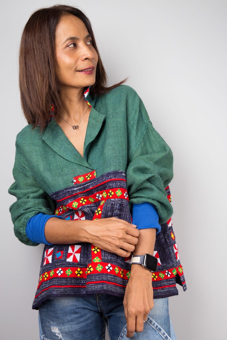 K&ouml;nnte beinhalten: Eine Frau tr&auml;gt ein gr&uuml;n-blau-rot gemustertes Hemd mit einer blau-wei&szlig;en Uhr am Handgelenk.