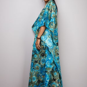 May include: A long, flowing blue and green patterned maxi dress with a draped neckline and short sleeves. The dress has a unique, abstract print that resembles swirling patterns.