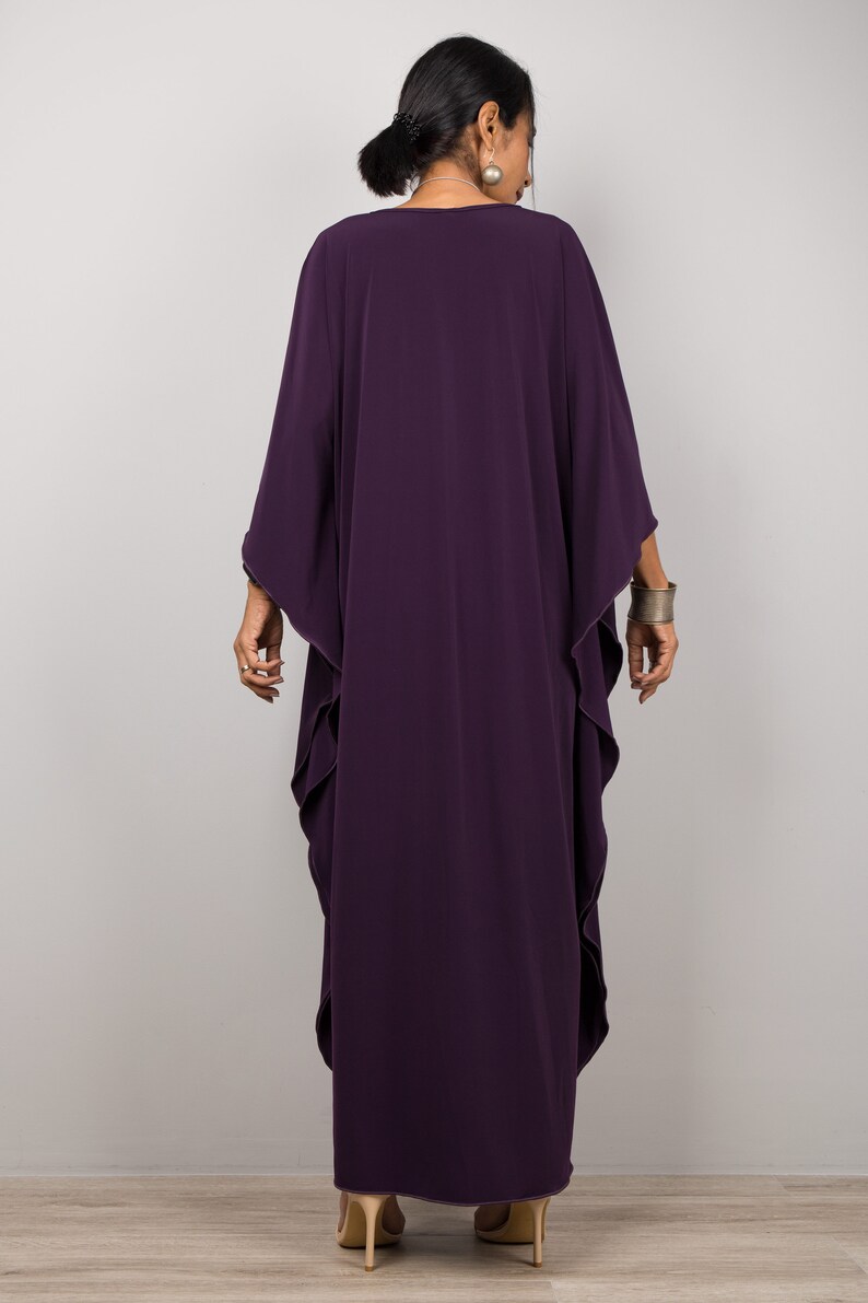May include: A long, flowing purple kaftan with a wide, open neckline. The kaftan has a relaxed fit and is made of a soft, drapey fabric.