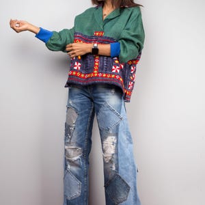 K&ouml;nnte beinhalten: Eine Frau tr&auml;gt ein gr&uuml;n-blaues gemustertes Hemd mit rotem und wei&szlig;em Besatz, blaue Jeans mit Patchwork-Details und gelbe Sandalen.