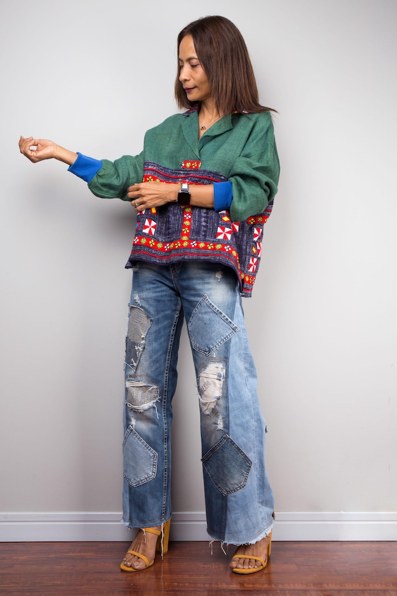 K&ouml;nnte beinhalten: Eine Frau tr&auml;gt ein gr&uuml;n-blaues gemustertes Hemd mit rotem und wei&szlig;em Besatz, blaue Jeans mit Patchwork-Details und gelbe Sandalen.