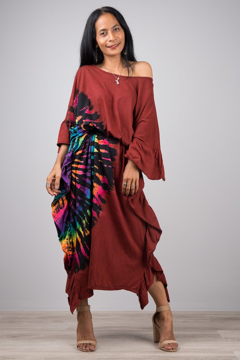May include: A maroon maxi dress with a colorful tie-dye pattern on the side. The dress has a loose fit and a ruffled hem.
