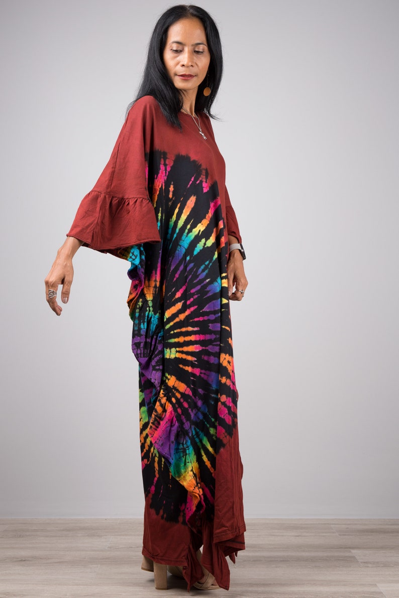 May include: A long, flowing, maroon maxi dress with a tie-dye pattern in shades of rainbow colors. The dress has a loose, comfortable fit and features a round neckline and bell sleeves.