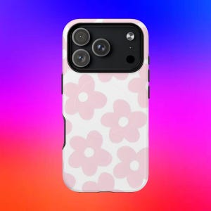 Può includere: Una custodia per smartphone con un motivo ripetuto di fiori rosa chiaro a cinque petali su sfondo bianco. La custodia presenta un ritaglio rettangolare nero per il modulo fotocamera nella parte superiore con tre aperture circolari e un flash.
