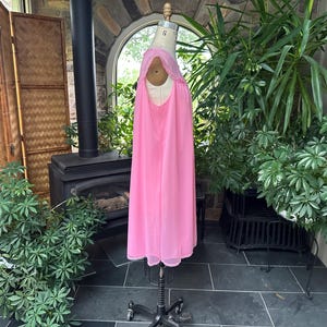 Puede incluir: Un camis&oacute;n rosa vintage exhibido en un maniqu&iacute;. El camis&oacute;n presenta un dise&ntilde;o fluido hasta el suelo con un delicado ribete de encaje alrededor del escote. El color rosa suave y la tela ligera sugieren una opci&oacute;n de ropa de dormir c&oacute;moda y elegante.