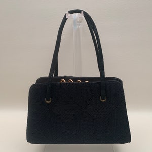 May include: A black beaded handbag with gold-toned hardware and a geometric pattern. The bag has two top handles.