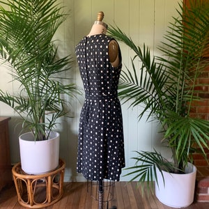 May include: A black and white sleeveless dress with a geometric pattern. The dress is fitted and has a knee-length skirt.