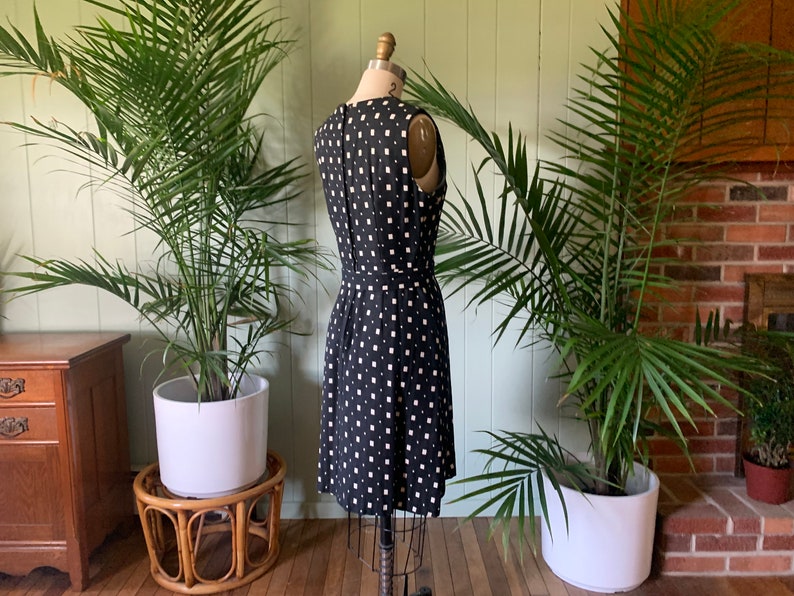 May include: A black and white sleeveless dress with a geometric pattern. The dress is fitted and has a knee-length skirt.