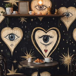 May include: A black wall with gold starbursts and heart-shaped wooden art featuring an eye design. A small table holds a croissant and coffee. A shelf above displays teacups, a mirror, and a small plant. The overall theme is a bohemian cafe.