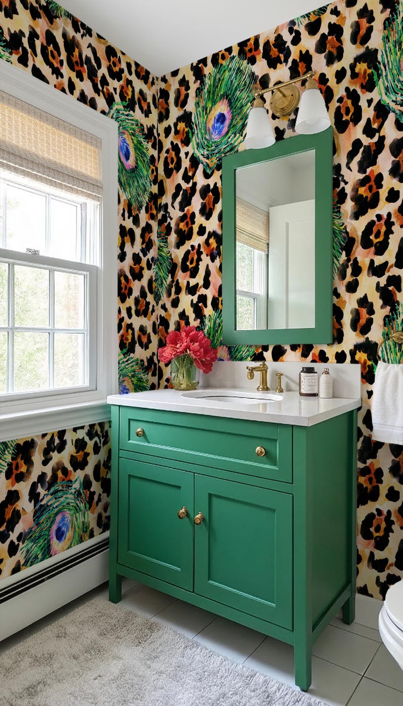 May include: A green bathroom vanity with gold hardware and a white countertop. The vanity is set against a wall with a leopard print and peacock feather design. A mirror with a green frame hangs above the vanity.