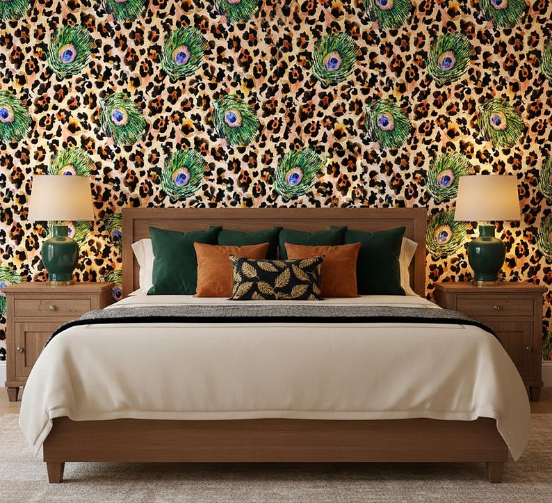 May include: A bedroom with a wooden bed frame, a cream-colored comforter, and decorative pillows. The pillows are in shades of green, orange, and black. The wallpaper features a leopard print with peacock feather accents. Two green lamps sit on nightstands.