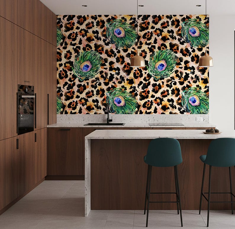 May include: A modern kitchen with dark wood cabinetry and a white countertop island. The focal point is a wall covered in wallpaper featuring a leopard print background with peacock feather accents. Two teal bar stools are positioned at the island.