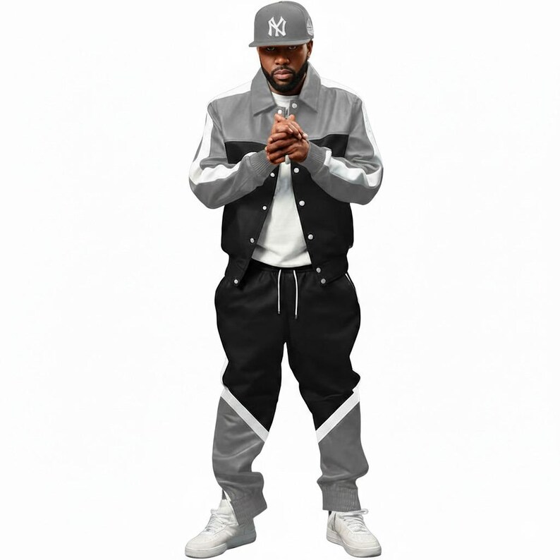 May include: A gray, black, and white track suit. The jacket is gray on top, black in the middle, and has white stripes on the sleeves. The pants are black with gray and white accents. A gray baseball cap with a logo is also visible.