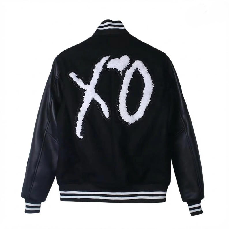 K&ouml;nnte beinhalten: Schwarze Collegejacke mit wei&szlig;em "XO"-Schriftzug auf dem R&uuml;cken. Die Jacke hat schwarze Leder&auml;rmel, einen gestreiften Kragen, B&uuml;ndchen und Saum. Ein klassisches, stilvolles Oberbekleidungsst&uuml;ck.