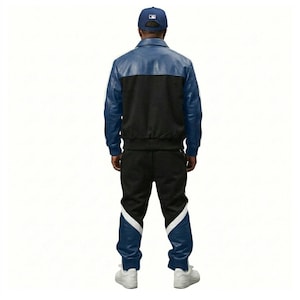May include: A blue and black leather jacket and matching track pants set. The jacket has a blue upper section and black lower section. The track pants are black with blue and white accents. A blue baseball cap completes the outfit.