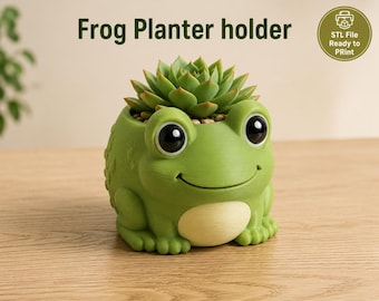 May include: A green frog-shaped planter holder with large black eyes and a cream-colored belly, containing a green succulent plant. The text "Frog Planter holder" and a circular badge stating "STL File Ready to PRint" are visible.