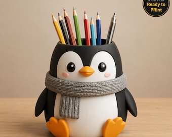May include: A black and white penguin pencil holder with an orange beak and feet, wearing a textured gray scarf. The holder contains several colored pencils. Text at the top reads Penguin Pencil Holder and STL File Ready to PRint.