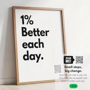 May include: A framed print with the text "1% Better each day." in bold black letters. Below the text are two QR codes and the words "SCAN ME!" and "Small steps, big change." The frame is a light brown color.