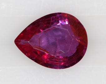 May include: A pear-shaped loose gemstone with a deep magenta and reddish-purple hue. The stone features a faceted surface that reflects light, creating internal patterns and depth within the translucent, vibrant colored crystalline structure.