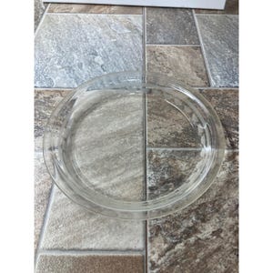Può includere: Una pirofila rotonda in vetro trasparente con un bordo leggermente rialzato. Il piatto ha un design semplice ed elegante, perfetto per cuocere e servire torte. Il vetro è trasparente, consentendo una visione chiara.