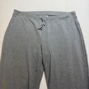 May include: Gray sweatpants with a drawstring waist. The pants are made of a soft material and have a relaxed fit. The drawstring is a matching gray color. The pants are a solid color and appear to be unworn.