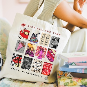 May include: Cream-colored tote bag with a pop art design. The bag features a red record player, butterflies, and the text "KISS ALL THE TIME." Additional text includes "READY STEADY GO!" and "DISCO MADE ME DO IT." The bag also has the text "DISCO, OCCASIONALLY."