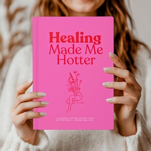 May include: A vibrant pink journal with the words "Healing Made Me Hotter" in red. It has a floral illustration and the text "A journal for becoming your hottest self - inside and out."