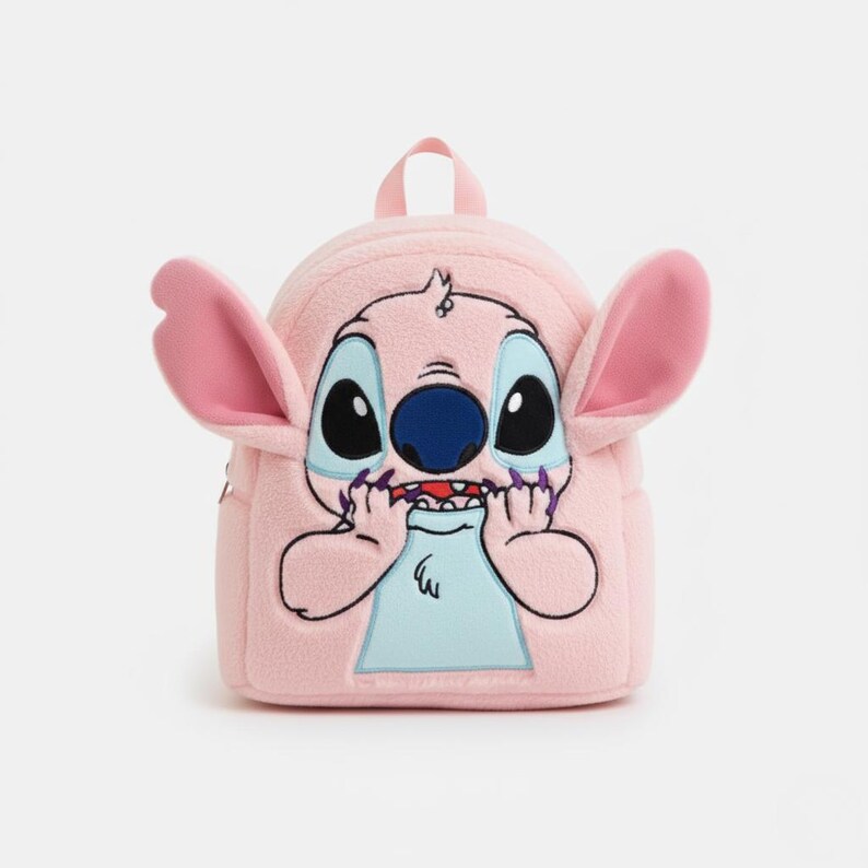 Puede incluir: Mochila de felpa rosa con el personaje Stitch de Lilo & Stitch. La mochila tiene orejas grandes y rosas, ojos negros grandes y una nariz azul. Las manos de Stitch est&aacute;n cerca de su boca y tiene un asa superior peque&ntilde;a.