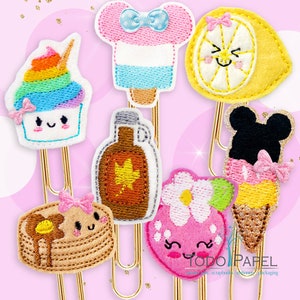 May include: Set of ten colorful embroidered paper clips with various cute designs, including a lemon, ice cream cone, maple syrup bottle, pancake, strawberry, and cupcake. The paper clips are gold and have a "TODO PAPEL" logo.