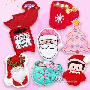 Pode incluir: Conjunto de 8 aplicações de feltro com tema natalino. As aplicações apresentam um cardeal vermelho, uma caixa de correio com o texto "Cartas para o Papai Noel", uma cabeça do Papai Noel, uma árvore de Natal rosa, uma caneca vermelha com marshmallows e um laço, uma caneca verde com marshmallows e um laço, um gnomo com um chapéu vermelho e barba, e um duende com um chapéu vermelho e cabelo castanho.