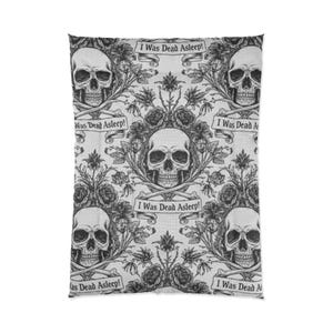 Könnte beinhalten: Eine Bettdecke mit einem sich wiederholenden Muster aus Totenköpfen, Rosen und Bannern. Die Totenköpfe sind mit gekreuzten Knochen darunter detailliert. Die Banner zeigen den Text "I Was Dead Asleep!" in einer gotischen Schriftart. Das Design ist in Schwarzweiß gehalten.
