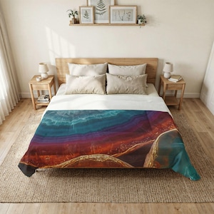 May include: A bed with a colorful comforter featuring a layered agate design in shades of blue, purple, and red. The comforter is draped over a bed with light-colored wooden furniture and neutral-toned pillows. The room has a natural, earthy aesthetic.
