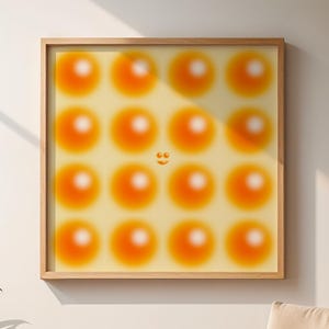 Può includere: Un'opera d'arte incorniciata con un motivo di cerchi sfocati arancioni e gialli su uno sfondo giallo chiaro. L'opera d'arte è esposta su una parete color crema, con una cornice in legno. Una sedia di legno e piante in vaso sono in primo piano.