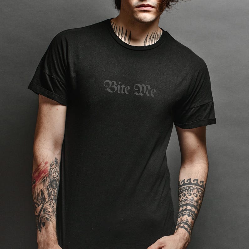 Black unisex gothic shirt with subtle “Bite Me” text design worn by model, minimalist dark humor graphic tee