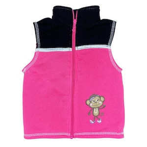 Puede incluir: Chaleco de forro polar rosa y negro con cierre de cremallera completo. El chaleco presenta un diseño de mono de dibujos animados, ribete plateado y cuello alto. Diseñado para niños.
