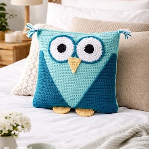 Könnte beinhalten: Gehäkeltes Eulen-Kissen in Blau, Weiß und Gelb. Das Kissen hat große, runde Augen mit schwarzen Pupillen, einen gelben Schnabel und kleine Füße. Der Text "PDF PATTERN" ist oben sichtbar.
