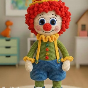 Op de afbeelding: Handgemaakte gehaakte clownpop met een rode krullende pruik, een gele hoed en een rode bloem. De pop draagt een groen shirt, een blauwe korte broek en blauwe schoenen. De tekst "PDF PATTERN" is zichtbaar.