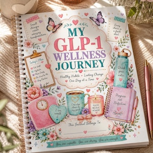 Op de afbeelding: Een spiraalgebonden wellness-dagboek getiteld My GLP-1 Wellness Journey. De kaft bevat illustraties van vlinders, bloemen, een waterfles, een weegschaal, een koffiemok en een kaars, met motiverende teksten zoals Progress not Perfection.