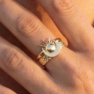 May include: A white ceramic mug with a black handle and the text "But First, Coffee" in a black, handwritten-style font. The mug is on a white surface.