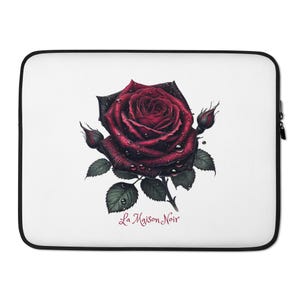 May include: A white laptop sleeve with a detailed illustration of a dark red rose with water droplets. The rose is surrounded by green leaves and buds. The text "La Maison Noir" is printed in a cursive font.