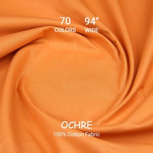May include: Ochre-coloured 100% cotton fabric, 239 cm wide, with the text "70 Colors". The fabric is draped, showing folds and texture. The word "OCHRE" is displayed prominently.