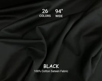 May include: Black 100% cotton sateen fabric, 94 inches wide. The image shows the fabric draped, with visible folds and shadows. Text indicates 26 colors are available. The word "BLACK" is prominently displayed.