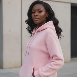 May include: A light pink hoodie with a drawstring hood and a kangaroo pocket. The hoodie is made of a soft material and has a relaxed fit. The person in the image is wearing the hoodie.