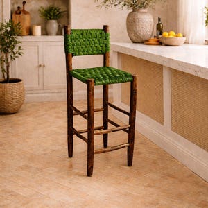 May include: A high bar stool with a woven green seat and back, set against a neutral kitchen backdrop. The frame is made of dark brown wood. The stool's height is suitable for a counter.