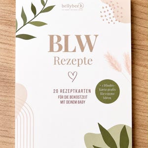 Könnte beinhalten: Ein rechteckiges Kartenset mit dem Titel BLW Rezepte, das 20 Rezeptkarten für die Beikostzeit enthält. Die weiße Karte ist mit beigen und olivgrünen botanischen Motiven, einem Herzsymbol und einem runden Aufkleber + 1 Blanko-Karte gratis bedruckt.
