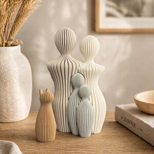 May include: A collection of decorative figurines in various sizes and colors. The figurines include a cat and several human-shaped figures with vertical striped designs. The color palette includes beige, light blue, and brown.