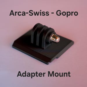 Może przedstawiać: Czarny adapter montażowy Arca-Swiss do Gopro z płaską kwadratową podstawą, trzyczęściowym interfejsem montażowym i srebrną metalową śrubą. Tekst Arca-Swiss - Gopro Adapter Mount jest widoczny powyżej i poniżej obiektu na zdjęciu.