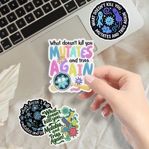 May include: A collection of colorful stickers with humorous text and illustrations. One sticker reads "What doesn't kill you MUTATES and tries AGAIN" in pastel colors. Other stickers feature similar phrases and cartoon microbes.