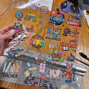 May include: A clear sheet of adhesive decals featuring colorful teacher-themed illustrations and text including Blessed Teacher, Your Work, Best Teacher Ever, Teaching is a work of heart, and Teach Love Inspire, with icons of books, pencils, and apples.
