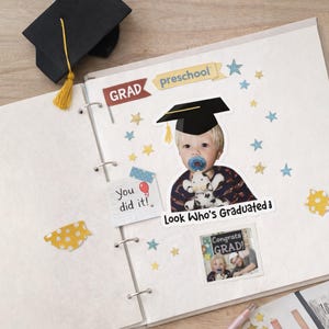 May include: A scrapbook page with graduation-themed decorations. Includes a photo of a baby wearing a graduation cap and holding a stuffed animal, with the text "Look Who's Graduated!" and "Congrats Grad!" Also features star stickers and a miniature graduation cap.